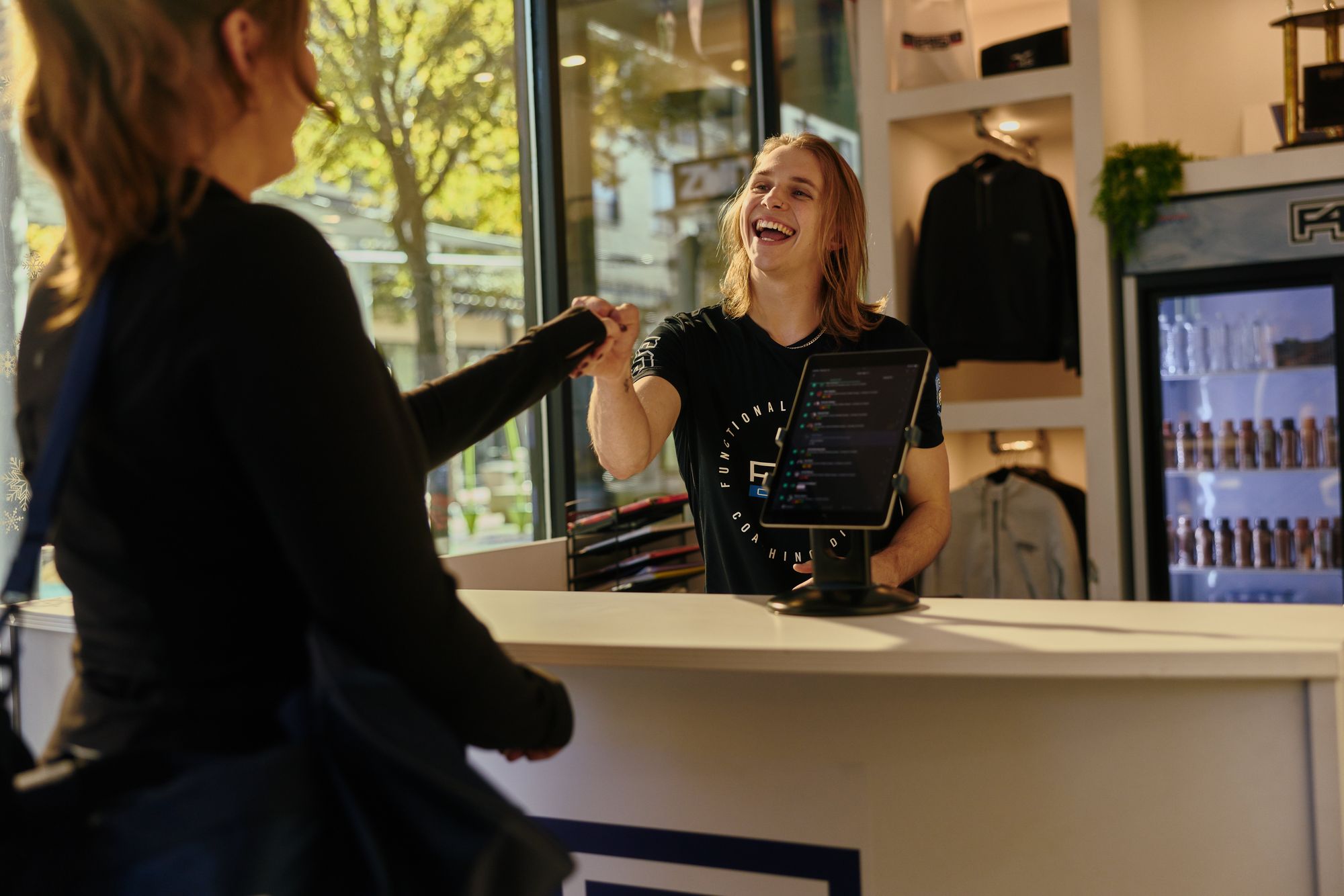 F45 coach greeting a member with a fist bump at the studio front desk